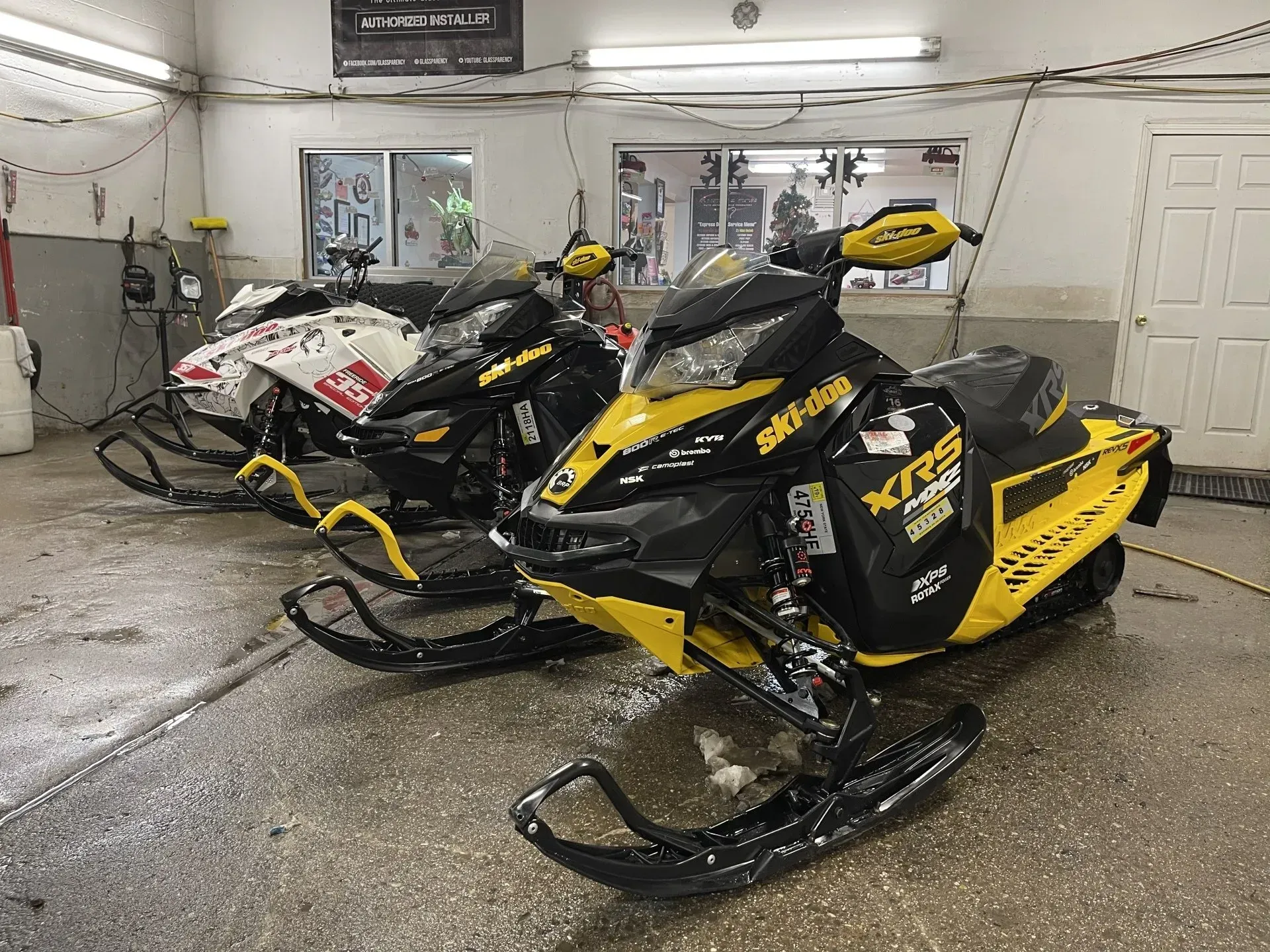 Two yellow and black snowmobiles parked inside a building.