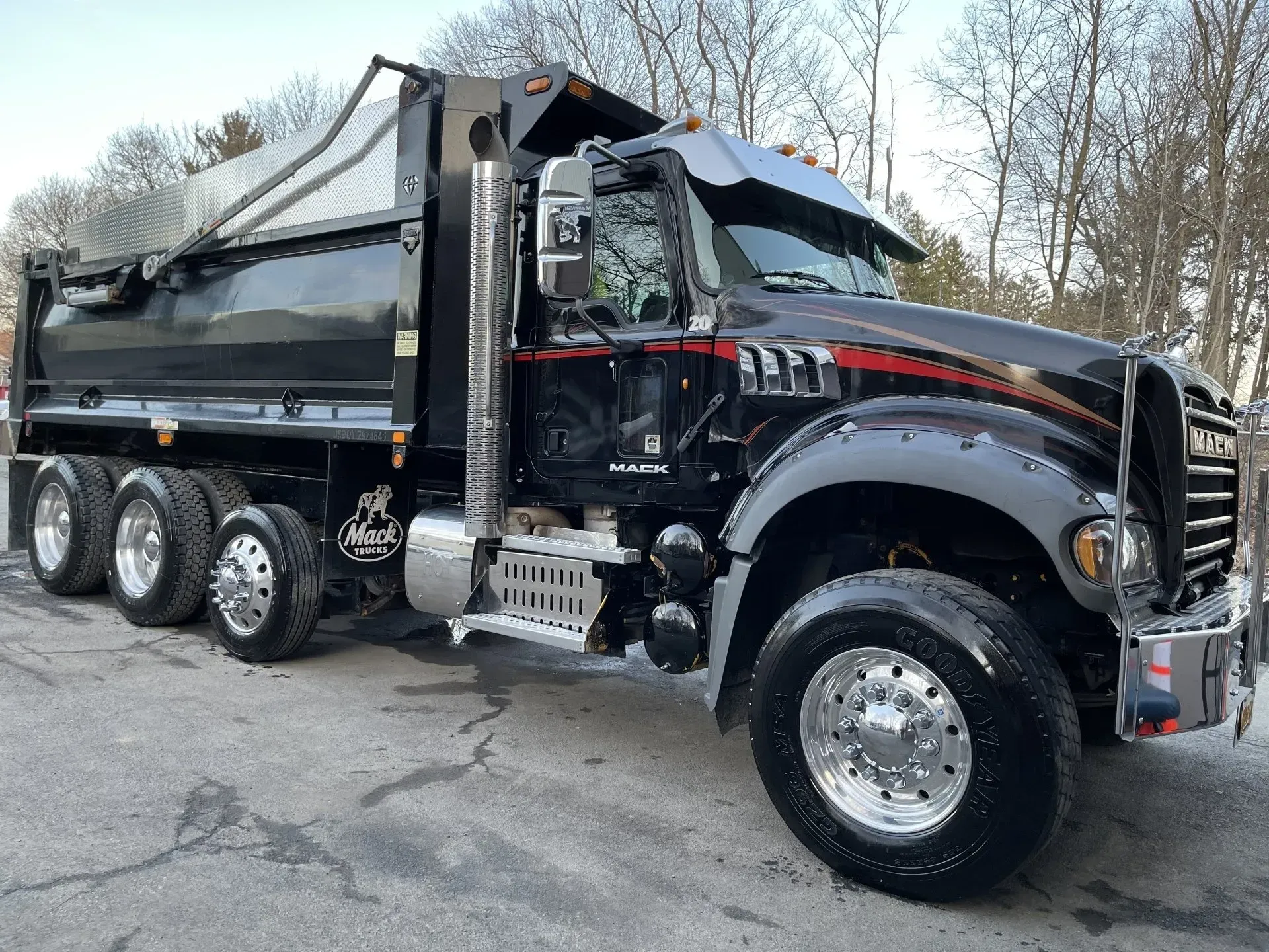 Black Mack dump truck on pavement, a partially visible snow-covered landscape in the background.
