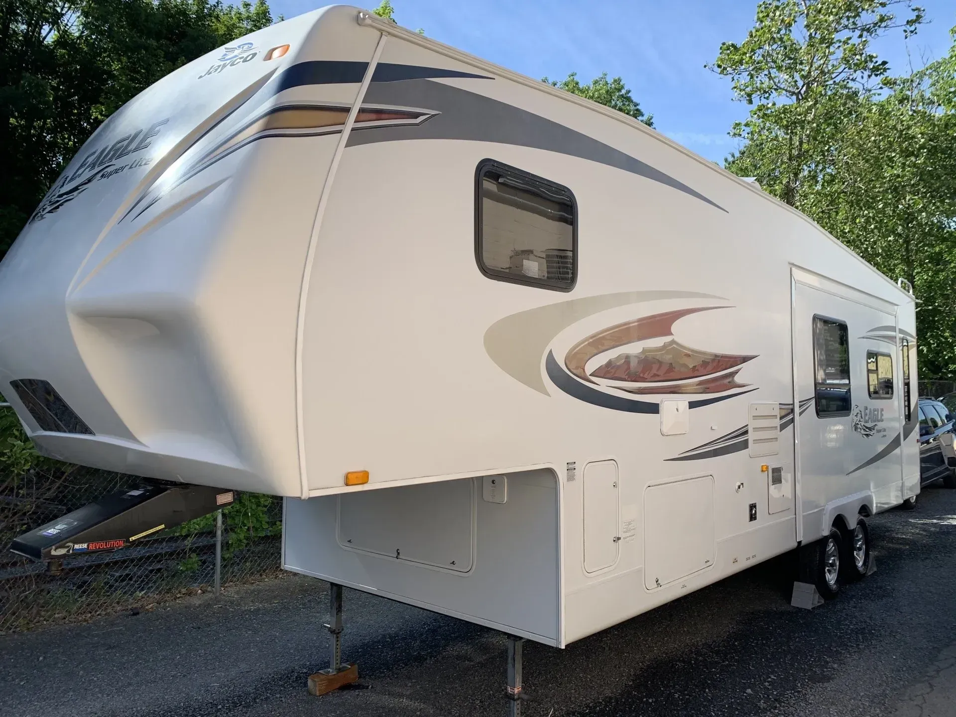 White RV parked outdoors with silver and brown decals.