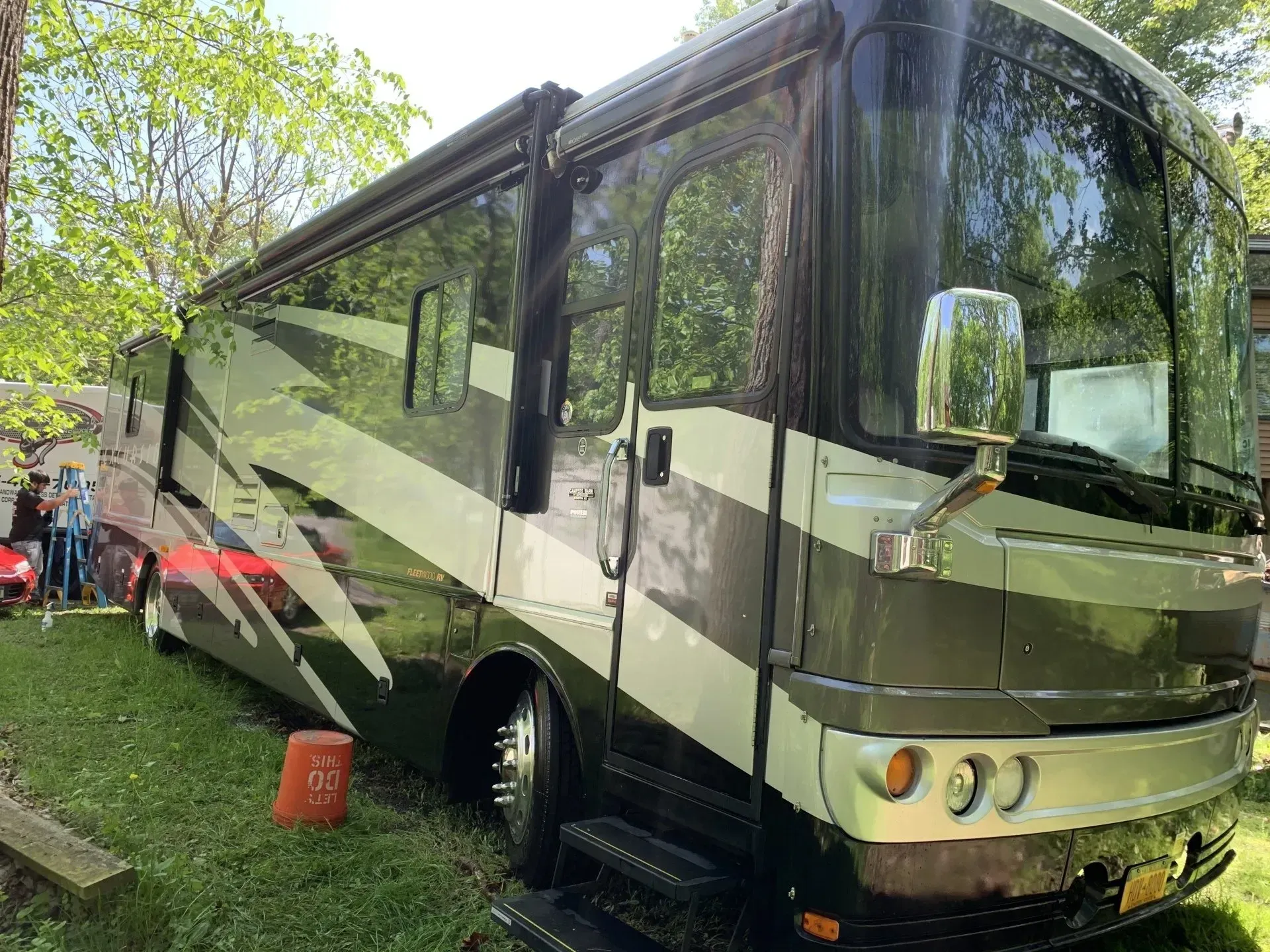 Large, black, white, and grey RV parked on grass.
