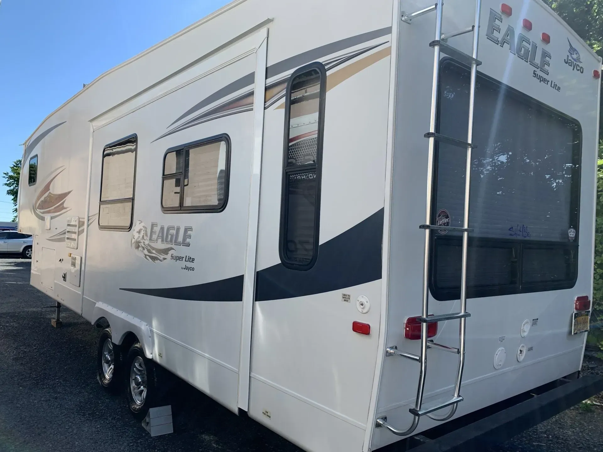 White Jayco Eagle travel trailer parked outside. Back ladder and tinted windows visible.
