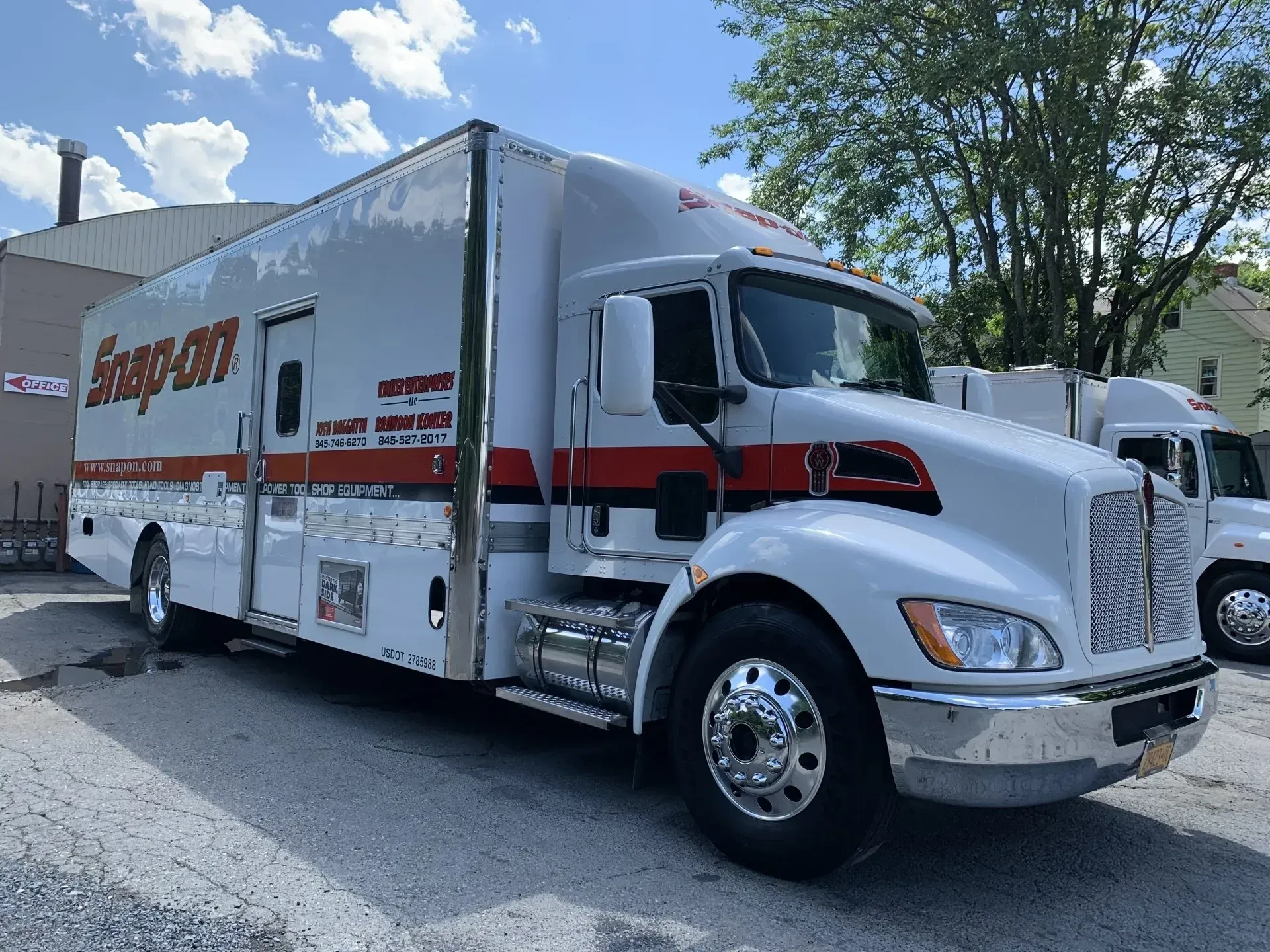 White Snap-on truck with red accents parked outside. Shiny chrome details and a sunny day setting.