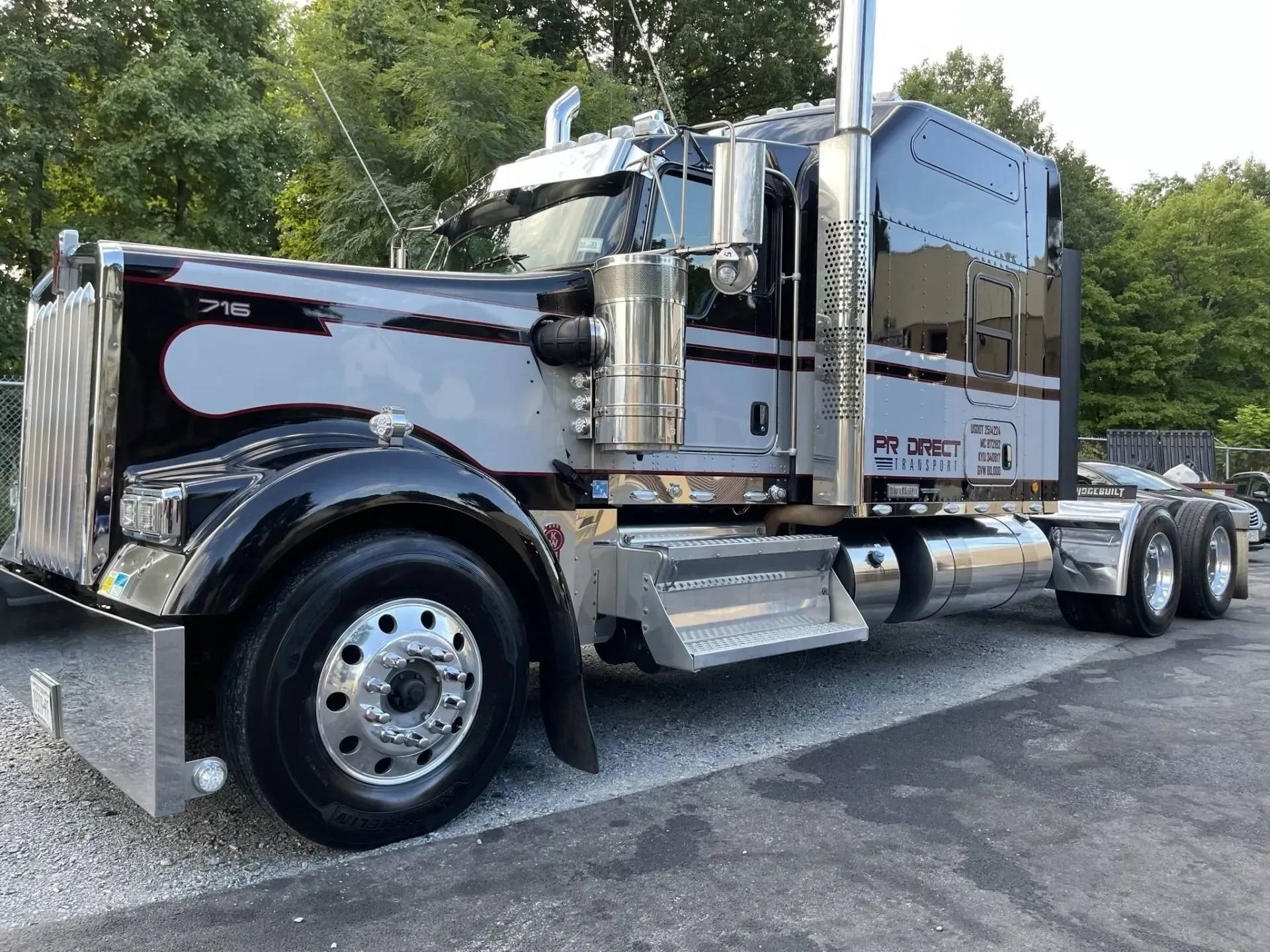 Black semi-truck with chrome accents parked outside. The truck has a gray stripe detail, and the setting is outdoors.