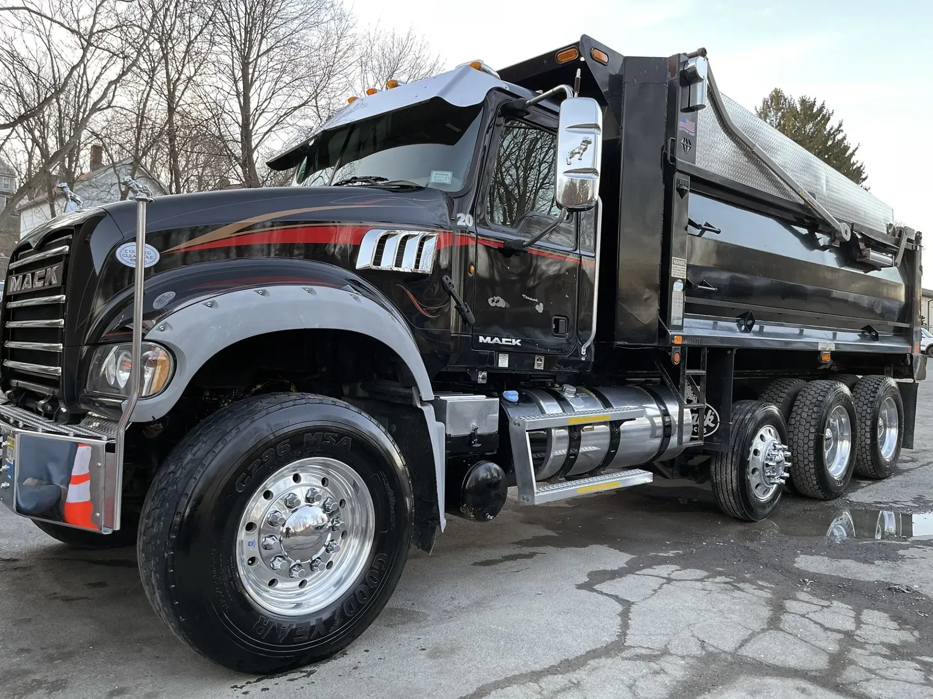 Black Mack dump truck with silver wheels, parked on a wet surface.