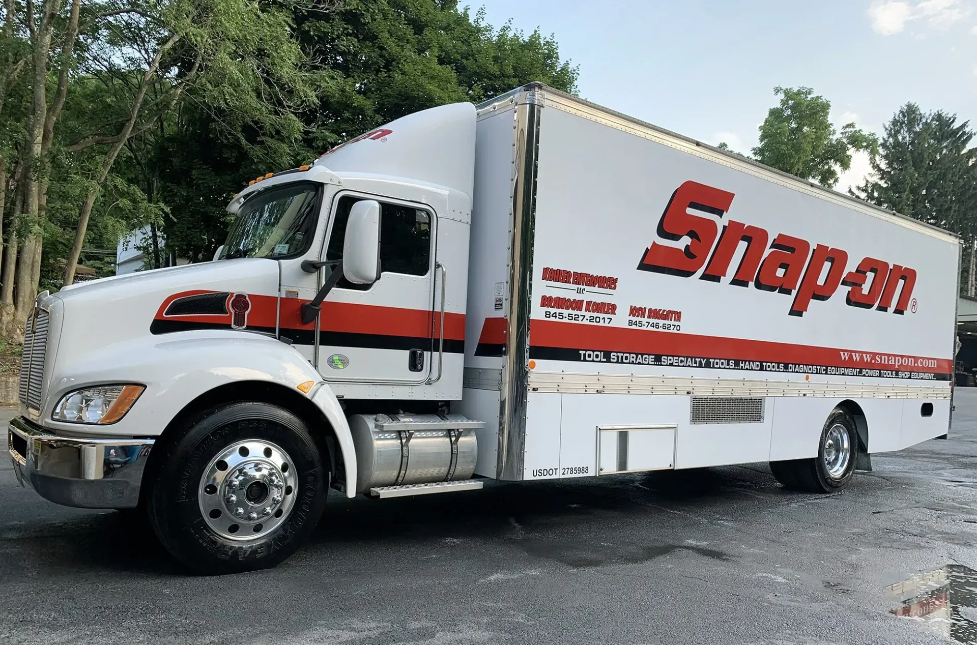 White Snap-on truck with red accents parked outside. Trees in the background.