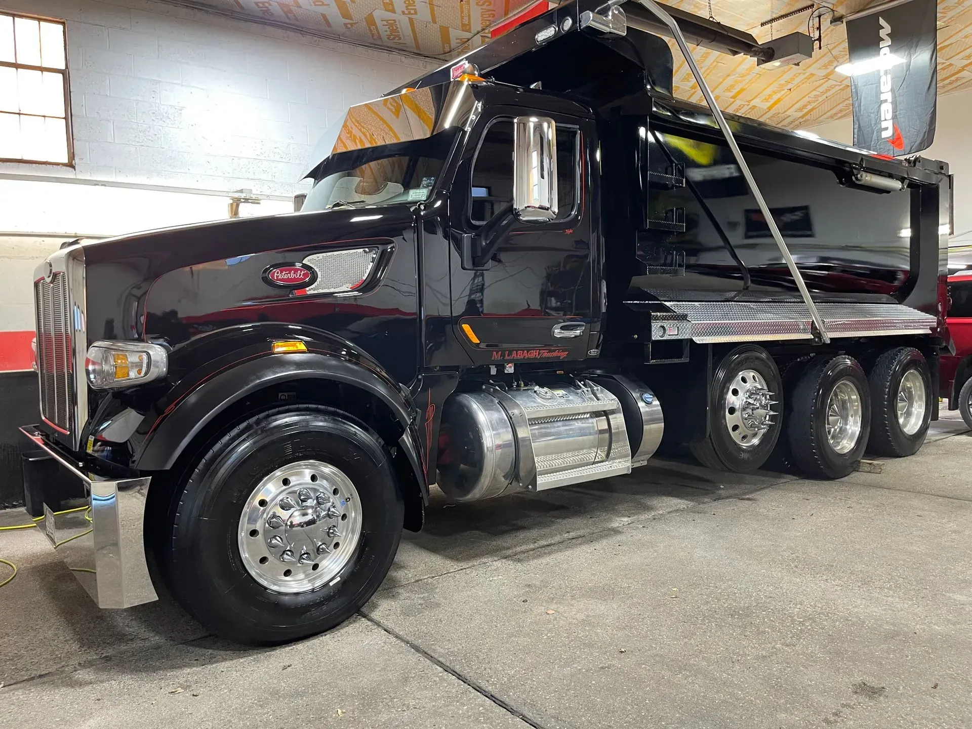 Black dump truck with chrome accents, parked in a garage.