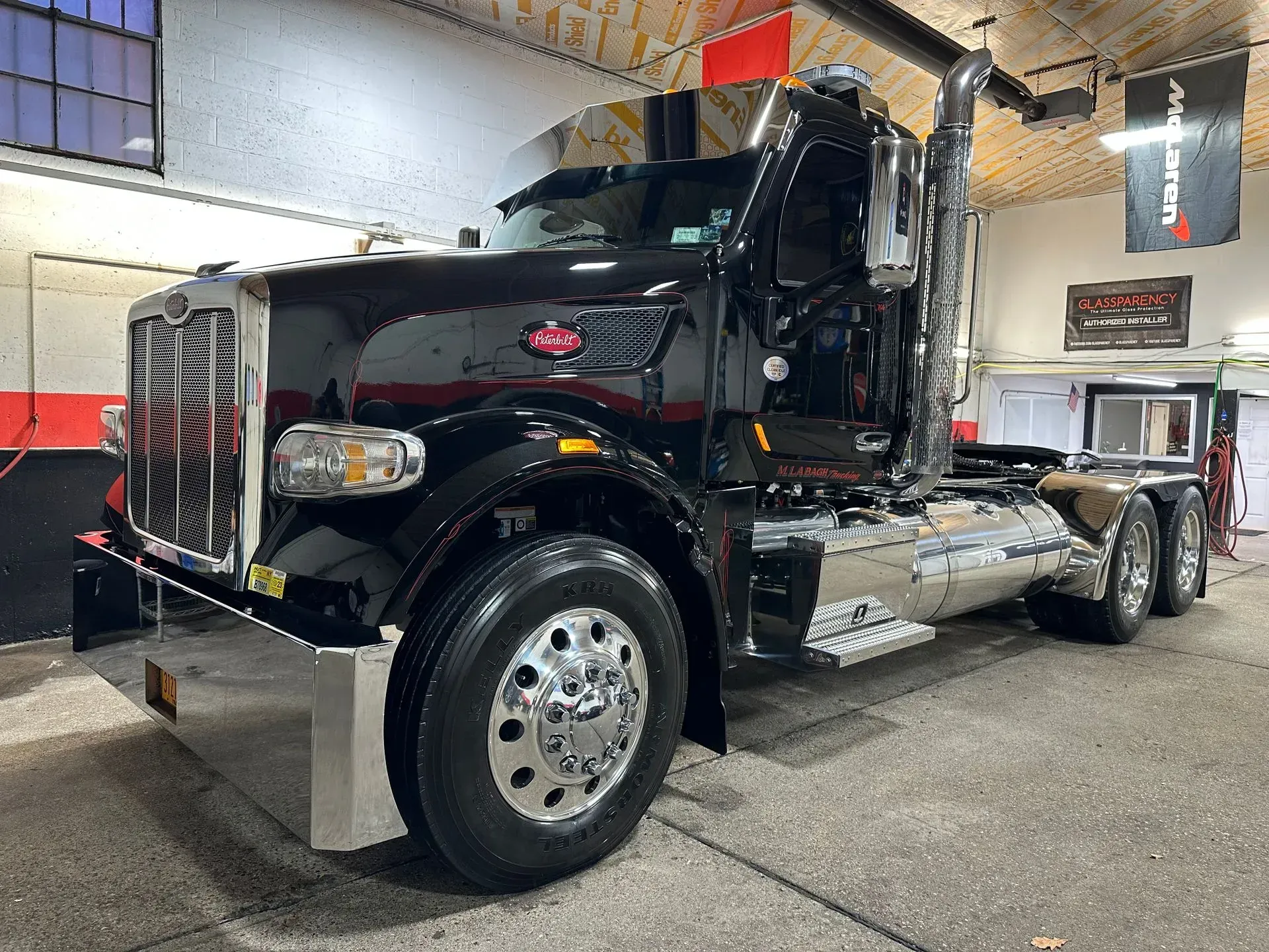 Black Peterbilt semi-truck with chrome detailing, parked in a garage.