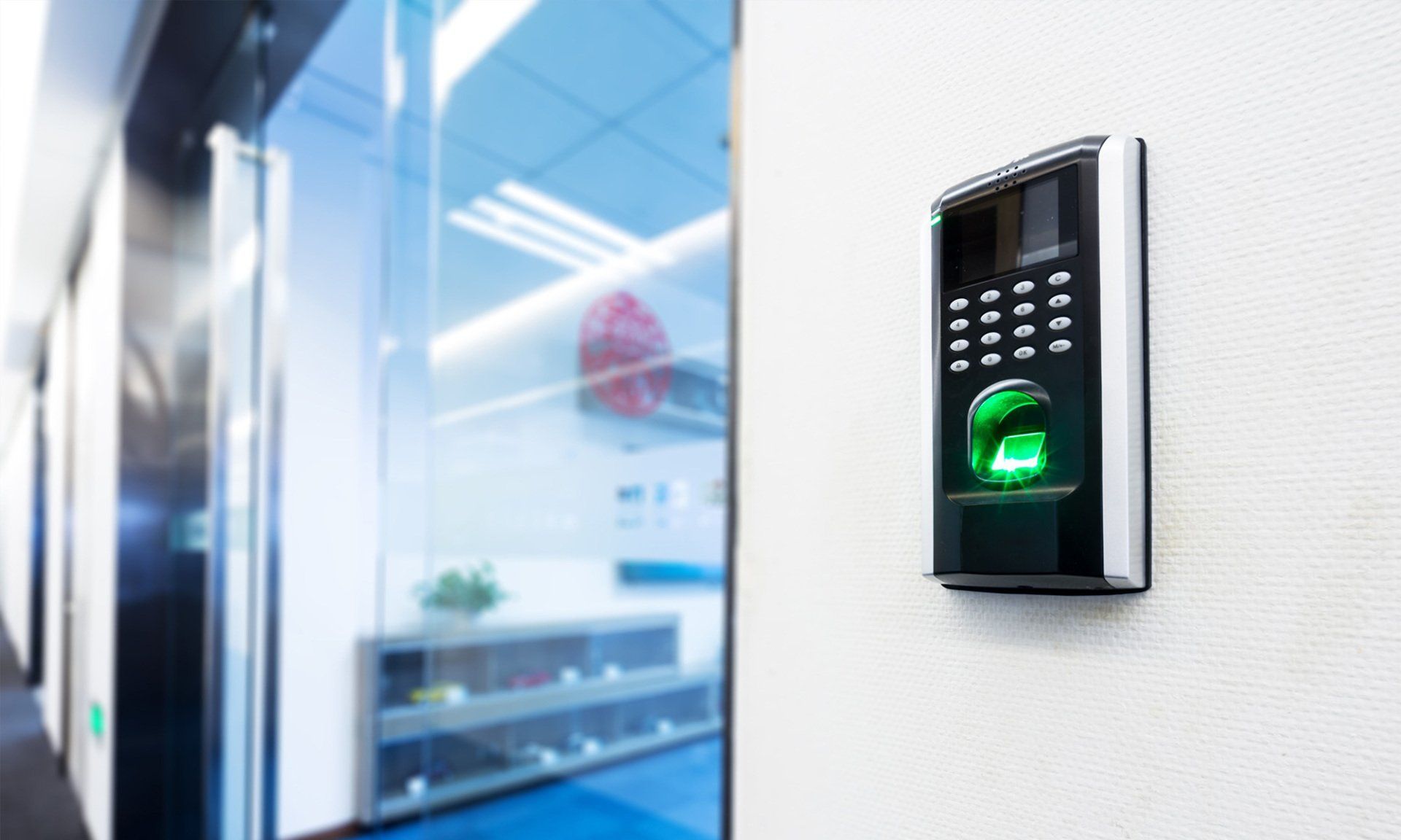 Black fingerprint and keypad access control device on a white wall.