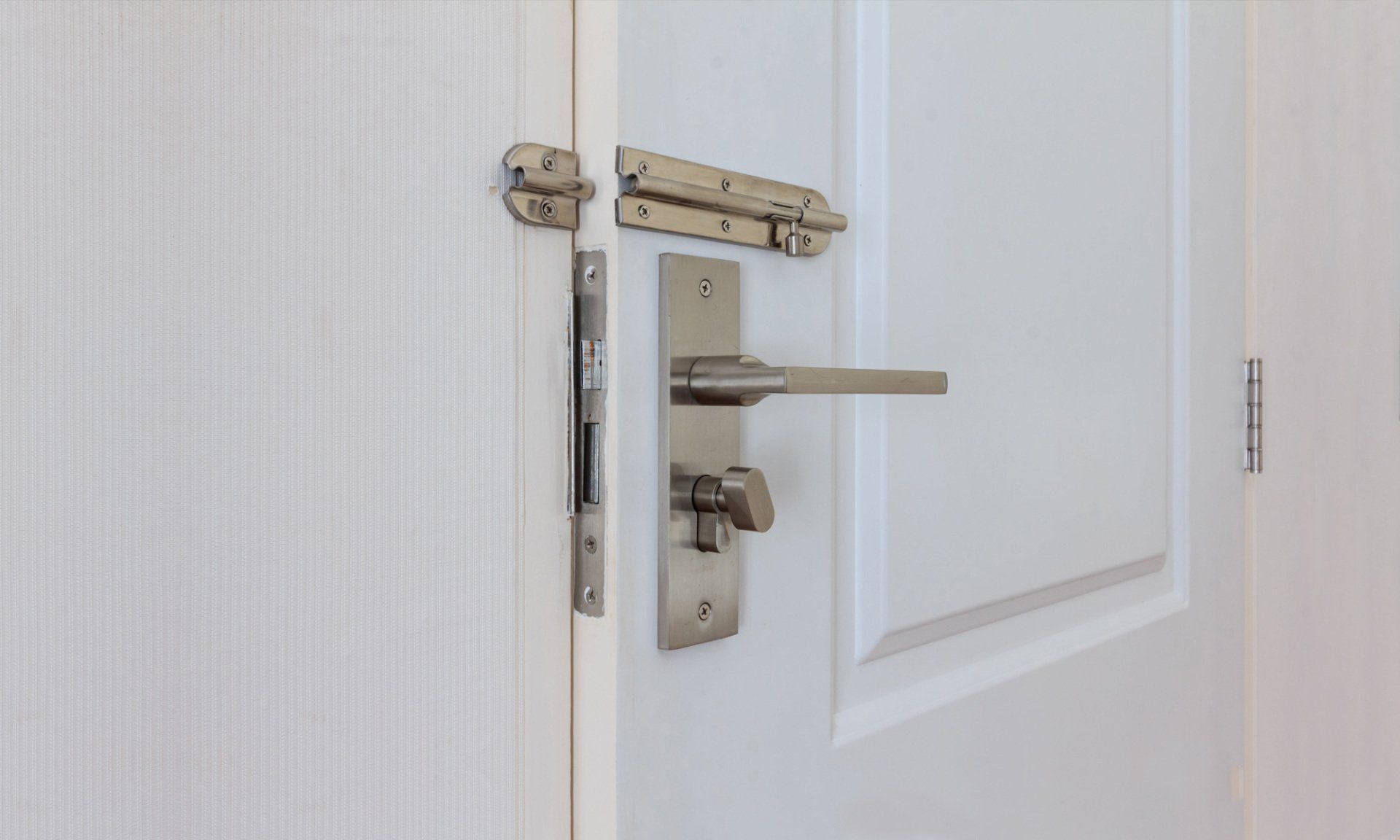 White door with silver hardware: handle, latch, and bolt.