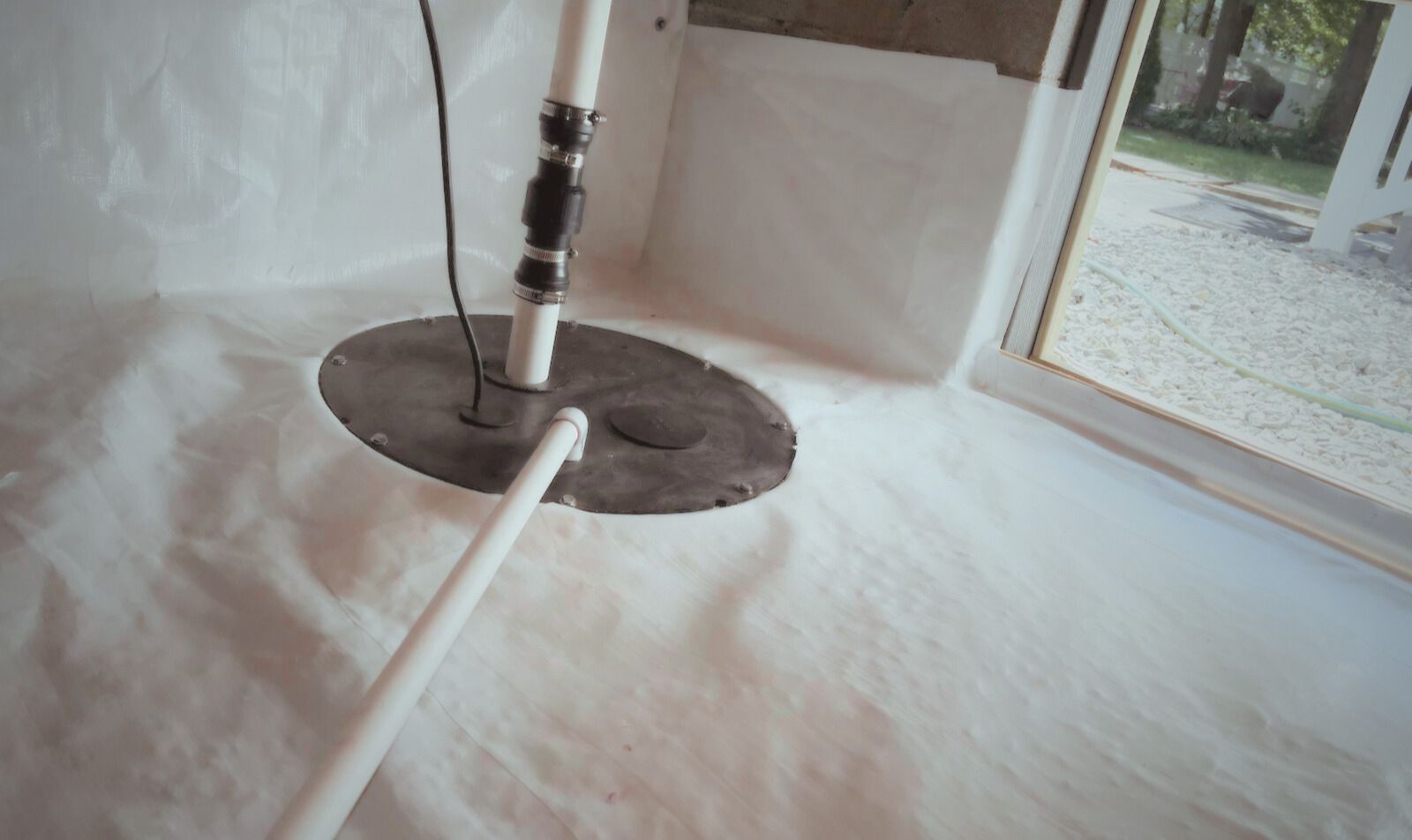 A white pole and round base inside a white tent or room, with a doorway and floor outside visible.