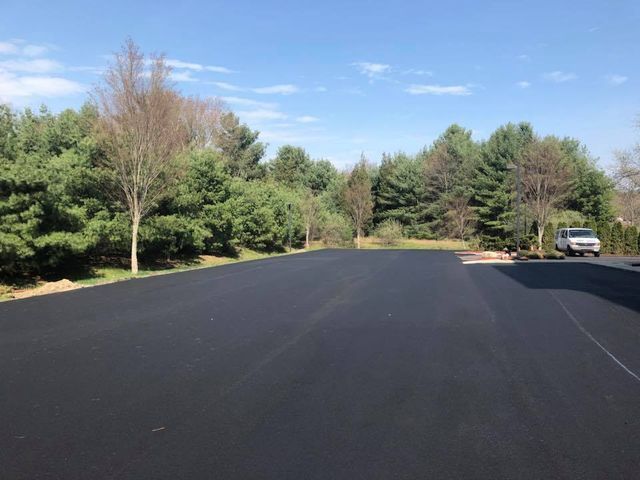 A car is parked on the side of a road next to trees.
