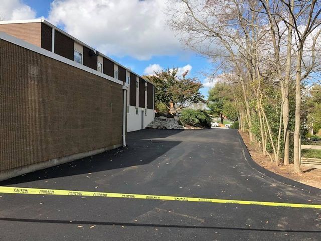 A brick building with a black driveway leading to it.
