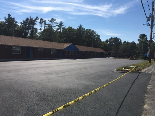 A building with a blue roof is behind a yellow caution tape