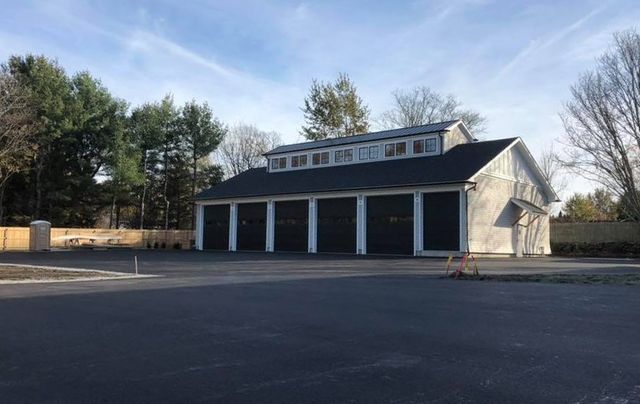 A large garage with a black roof is sitting in the middle of a parking lot.
