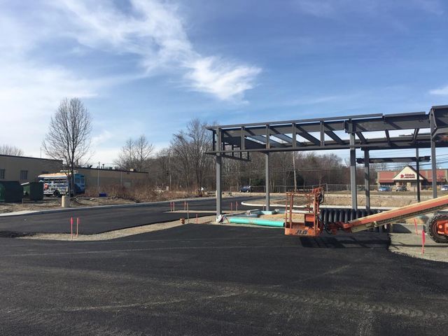 A large metal structure is being built in a parking lot.