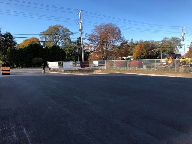 A truck is driving down a road next to a fence.