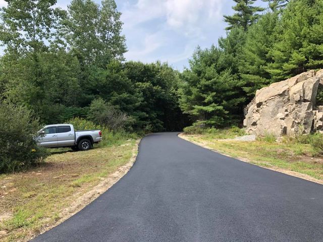 A truck is parked on the side of a road surrounded by trees.