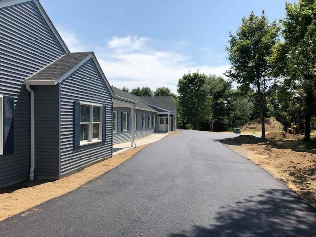 A row of houses along a road with trees in the background