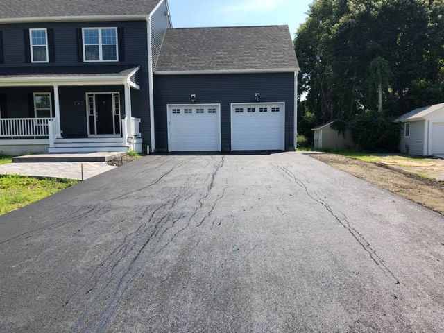 A driveway leading to a house with two garage doors