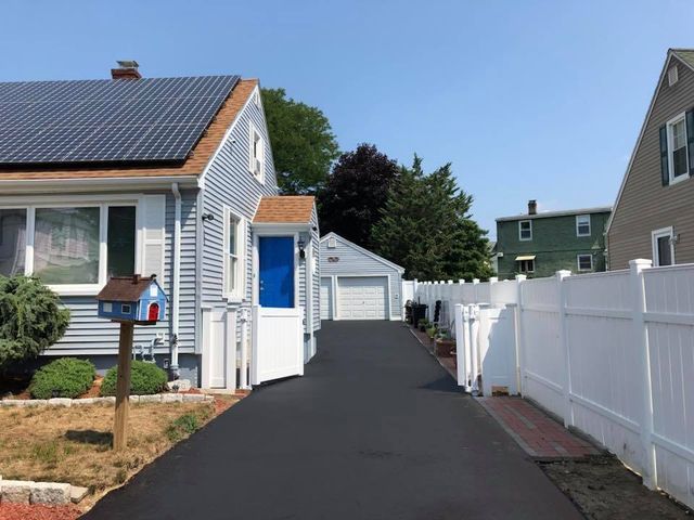 A driveway leading to a house with solar panels on the roof