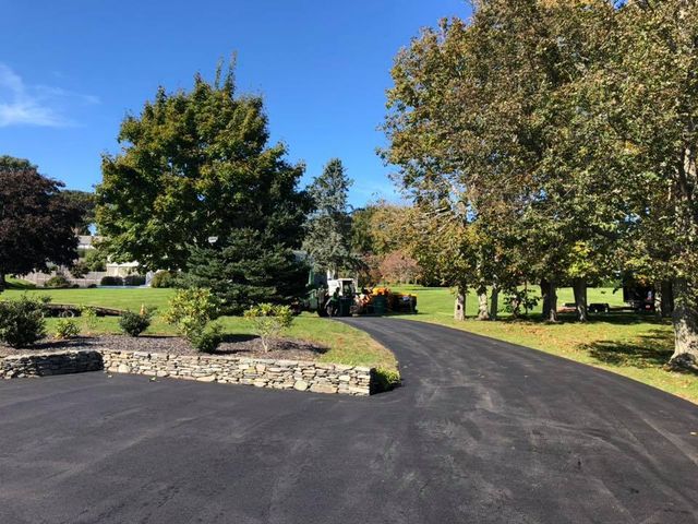 A driveway leading to a house with trees on both sides.