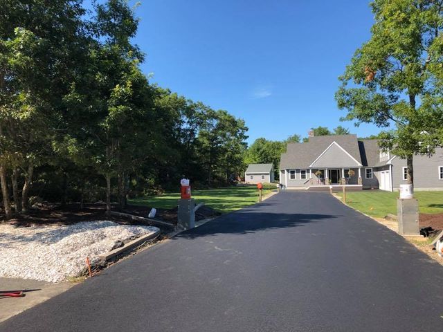 A man is standing on the side of a road next to a house.
