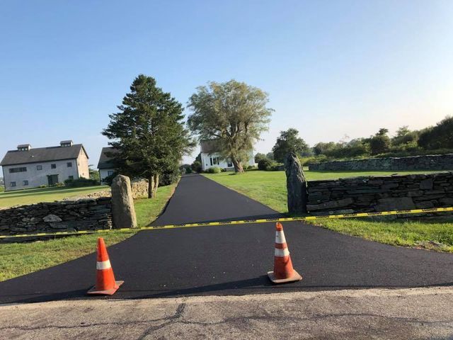 Two orange and white traffic cones are on the side of a road.