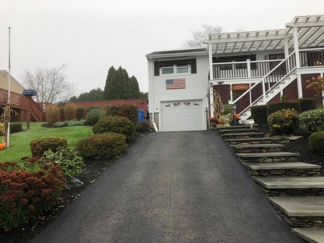 A driveway leading to a house with stairs leading up to it