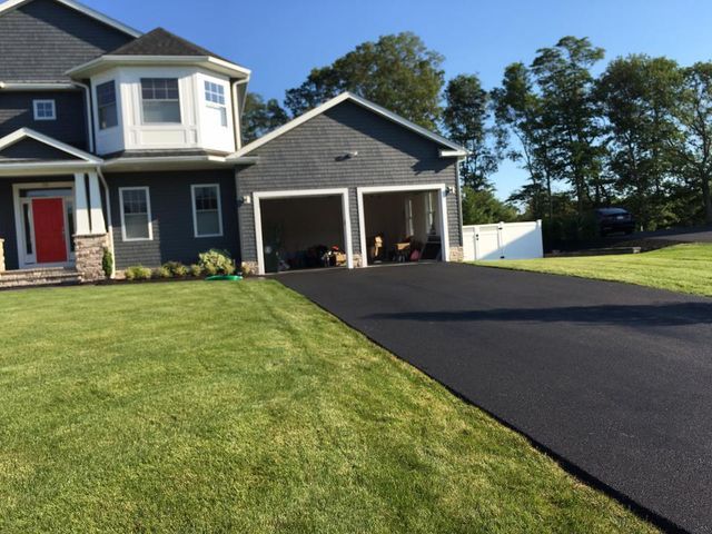 A large house with a black driveway leading to it