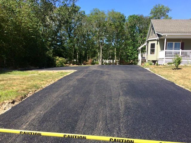 A driveway with a caution tape along the side of it and a house in the background.