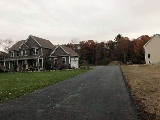 A large house is sitting on the side of a road next to a smaller house.