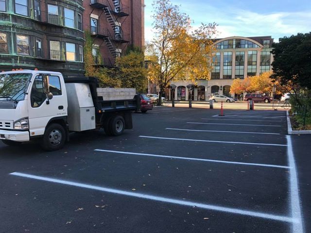A dump truck is parked in a parking lot in front of a building.