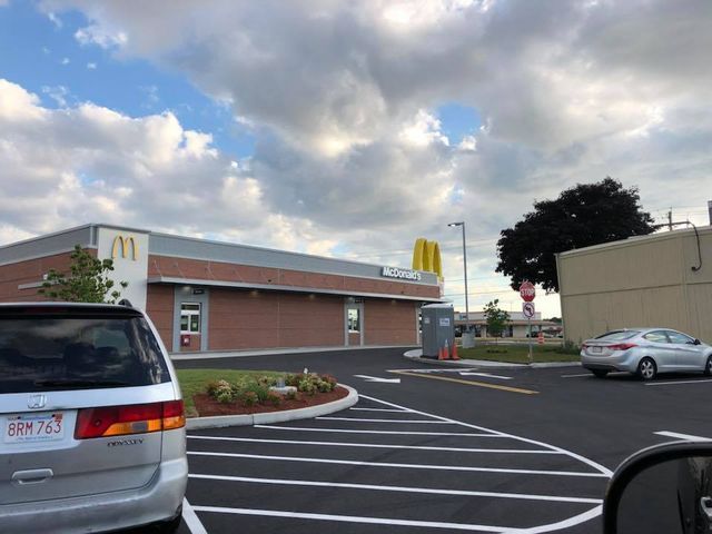 A silver minivan is parked in front of a mcdonald 's