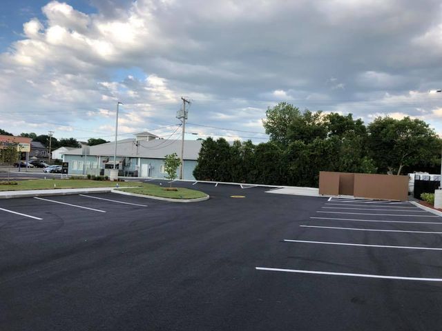 A parking lot with a building in the background and a cloudy sky