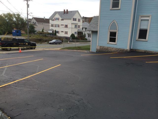 A parking lot with a blue house in the background