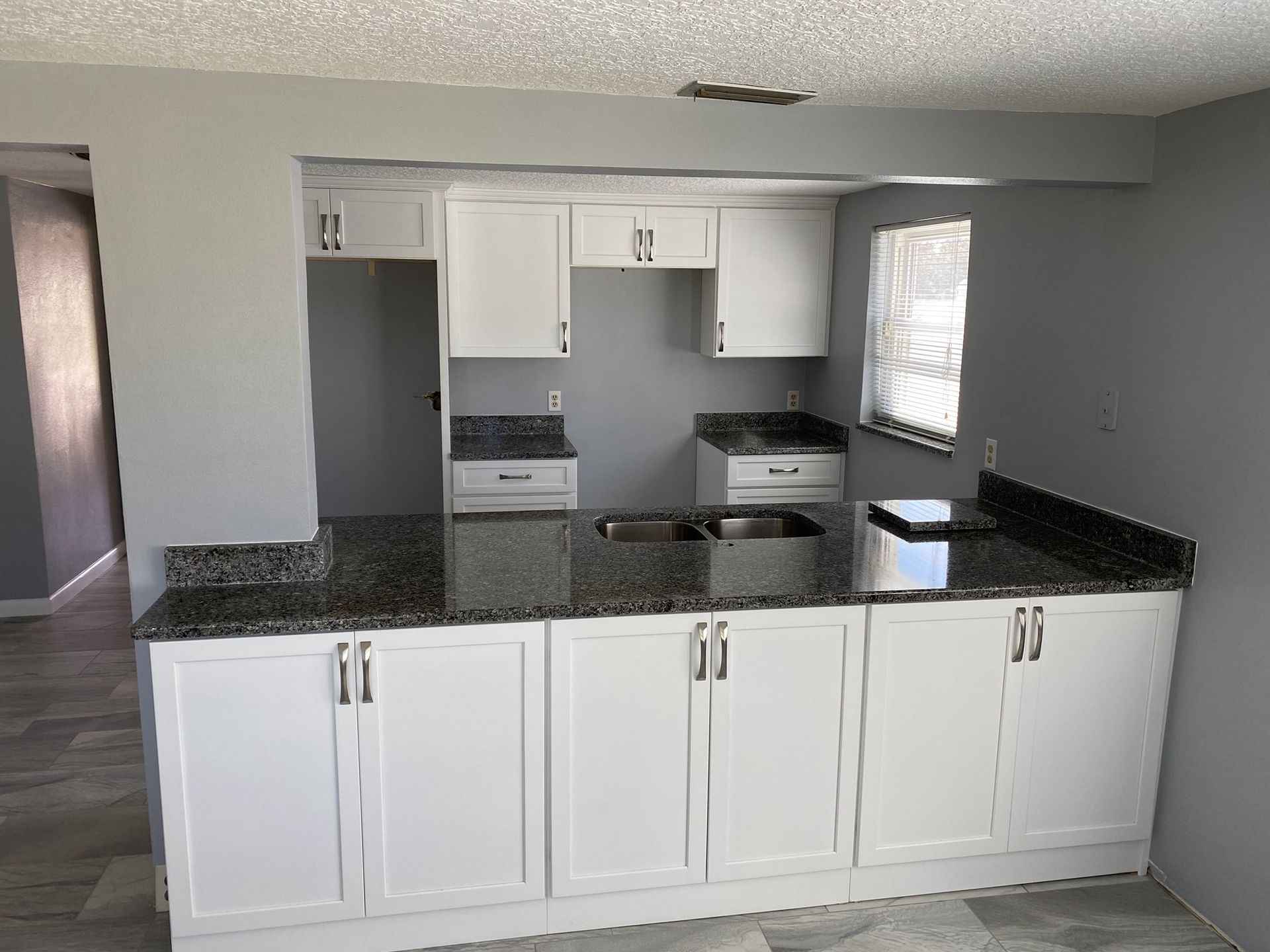 A kitchen with granite counter tops and white cabinets