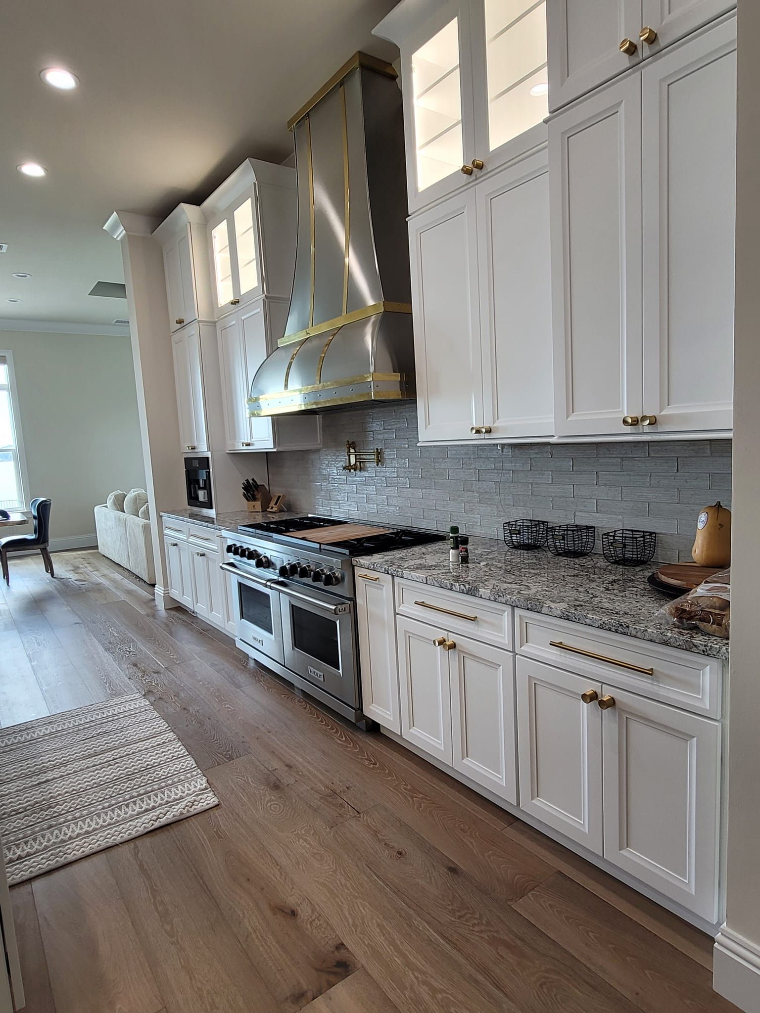 A kitchen with white cabinets , granite counter tops , and stainless steel appliances.