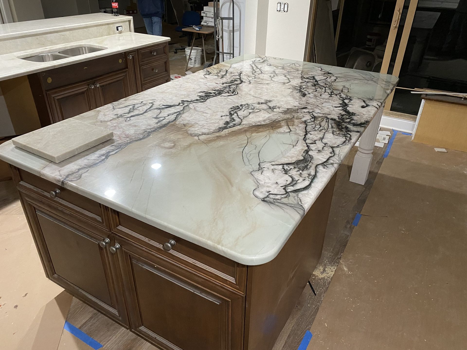 A kitchen island with a marble counter top and wooden cabinets.