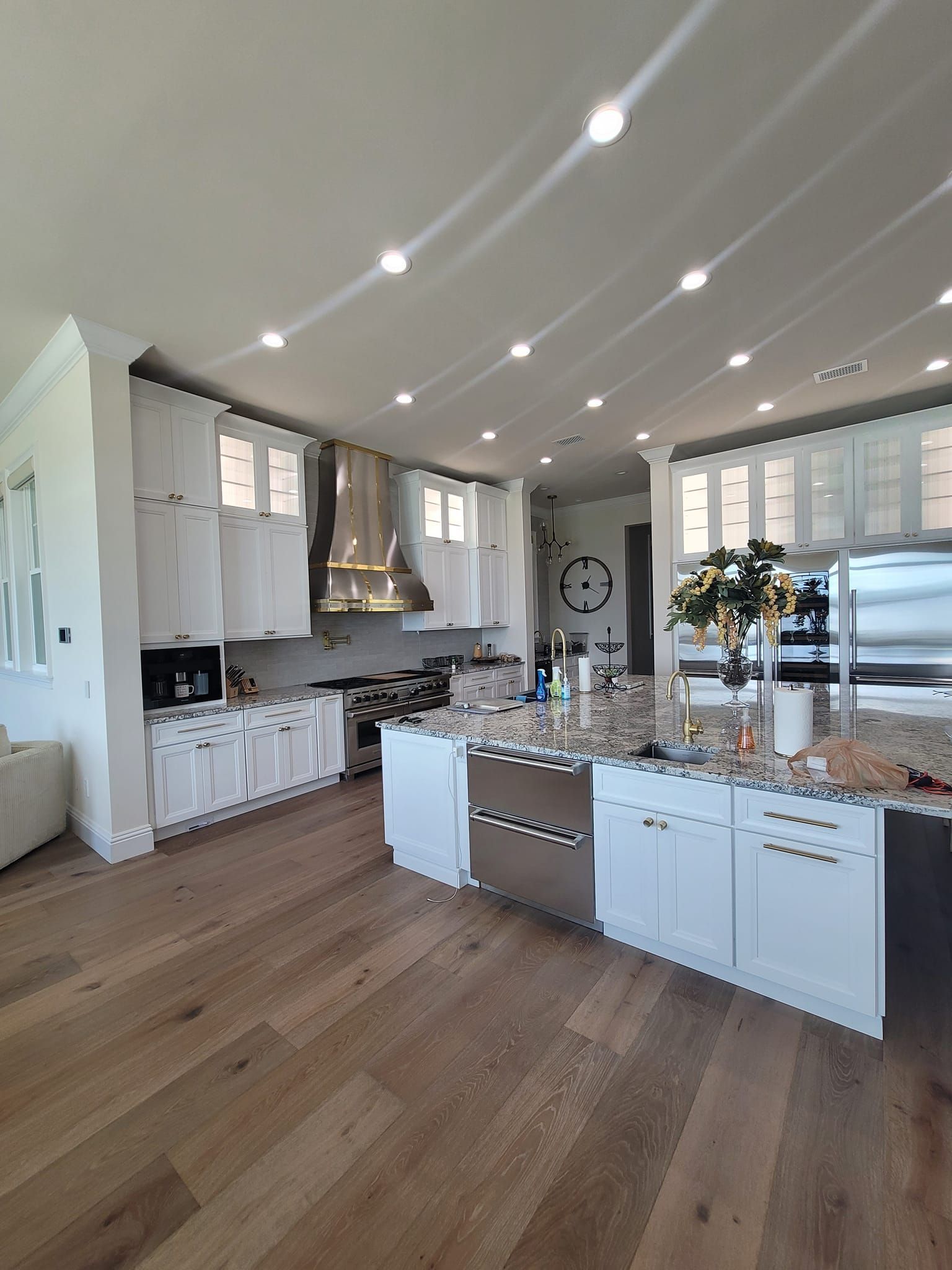 A kitchen with white cabinets , stainless steel appliances , granite counter tops and hardwood floors.
