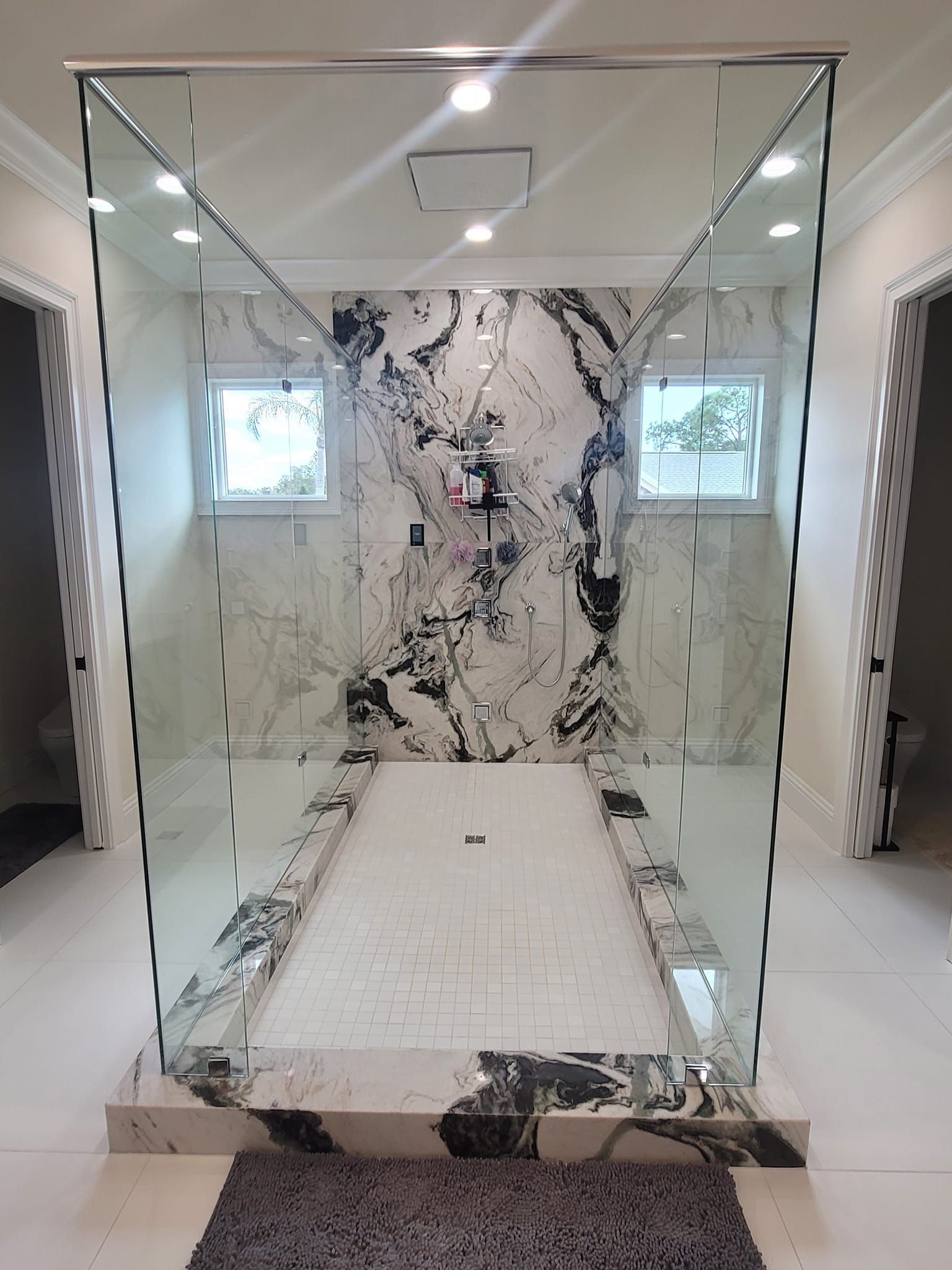 A bathroom with a walk in shower and a marble wall.