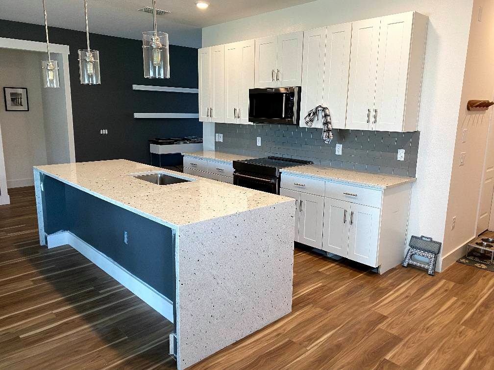 A kitchen with white cabinets and a large island in the middle.