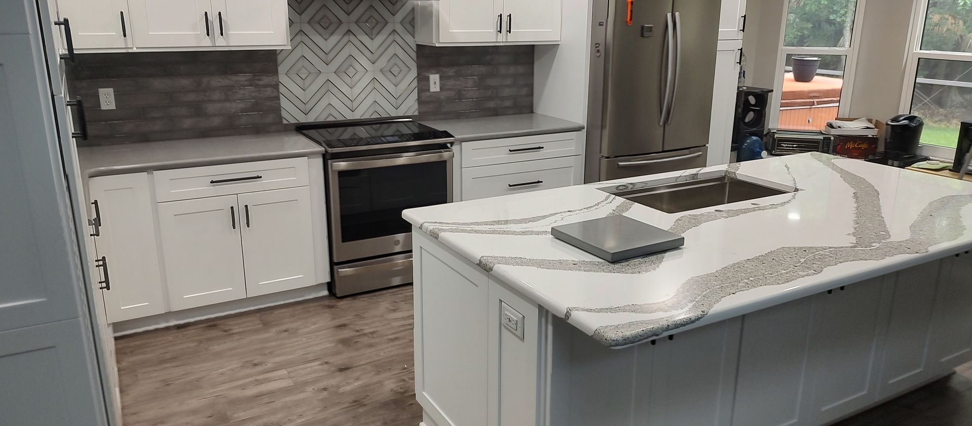A kitchen with white cabinets , granite counter tops , stainless steel appliances and a large island.