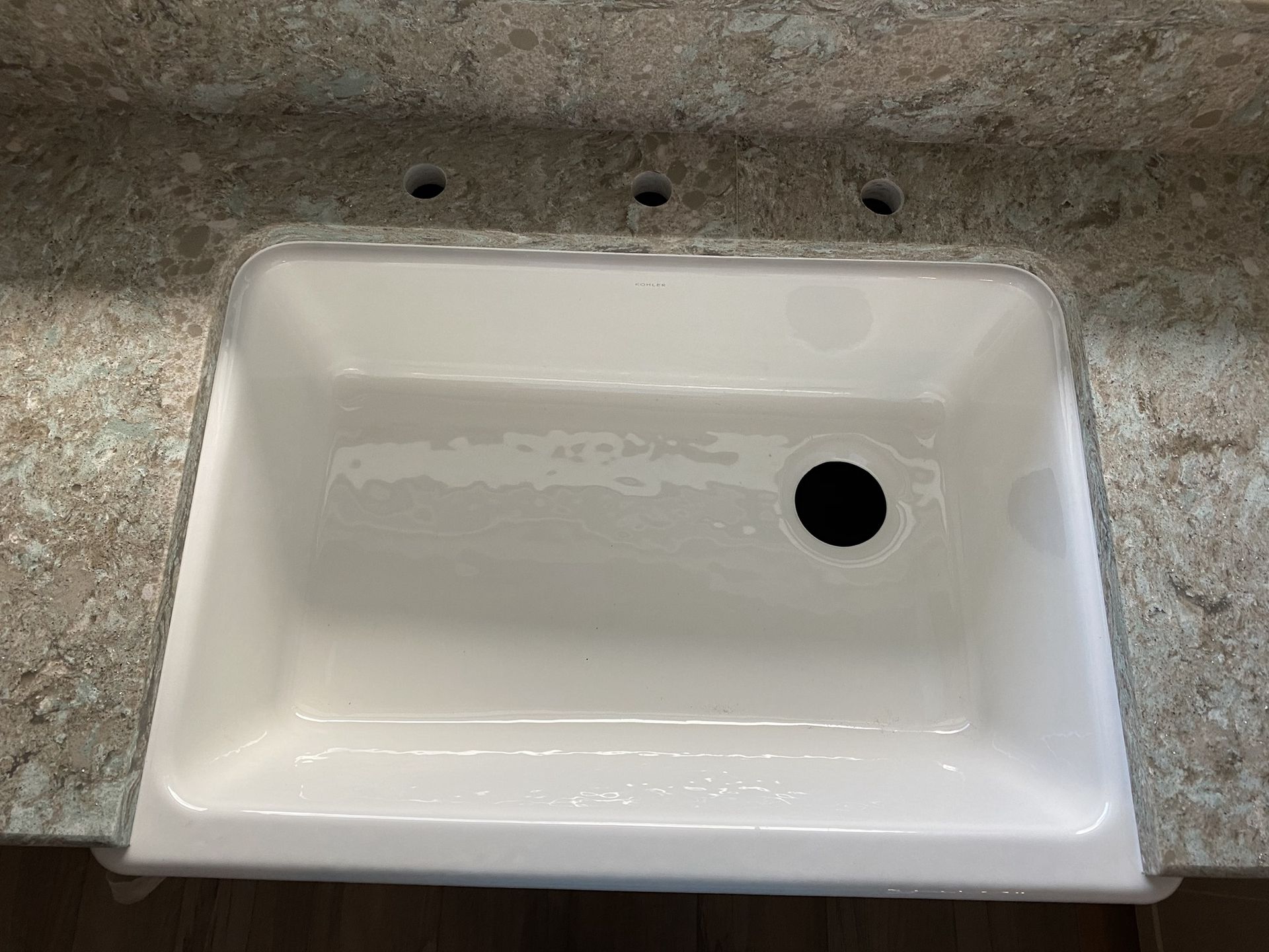 A white sink is sitting on top of a granite counter top.