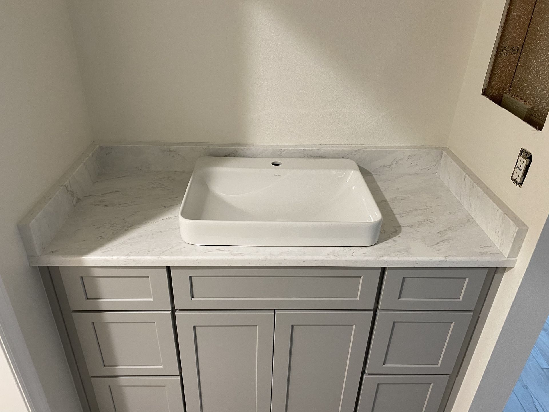 A bathroom vanity with a white sink and gray cabinets.