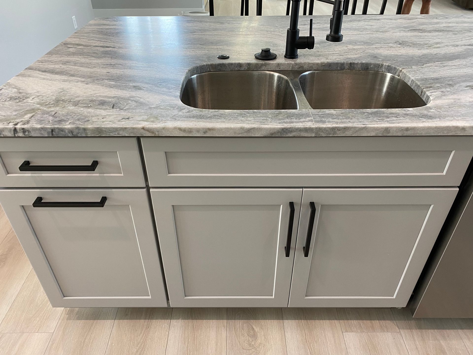 A kitchen with white cabinets and a stainless steel sink.
