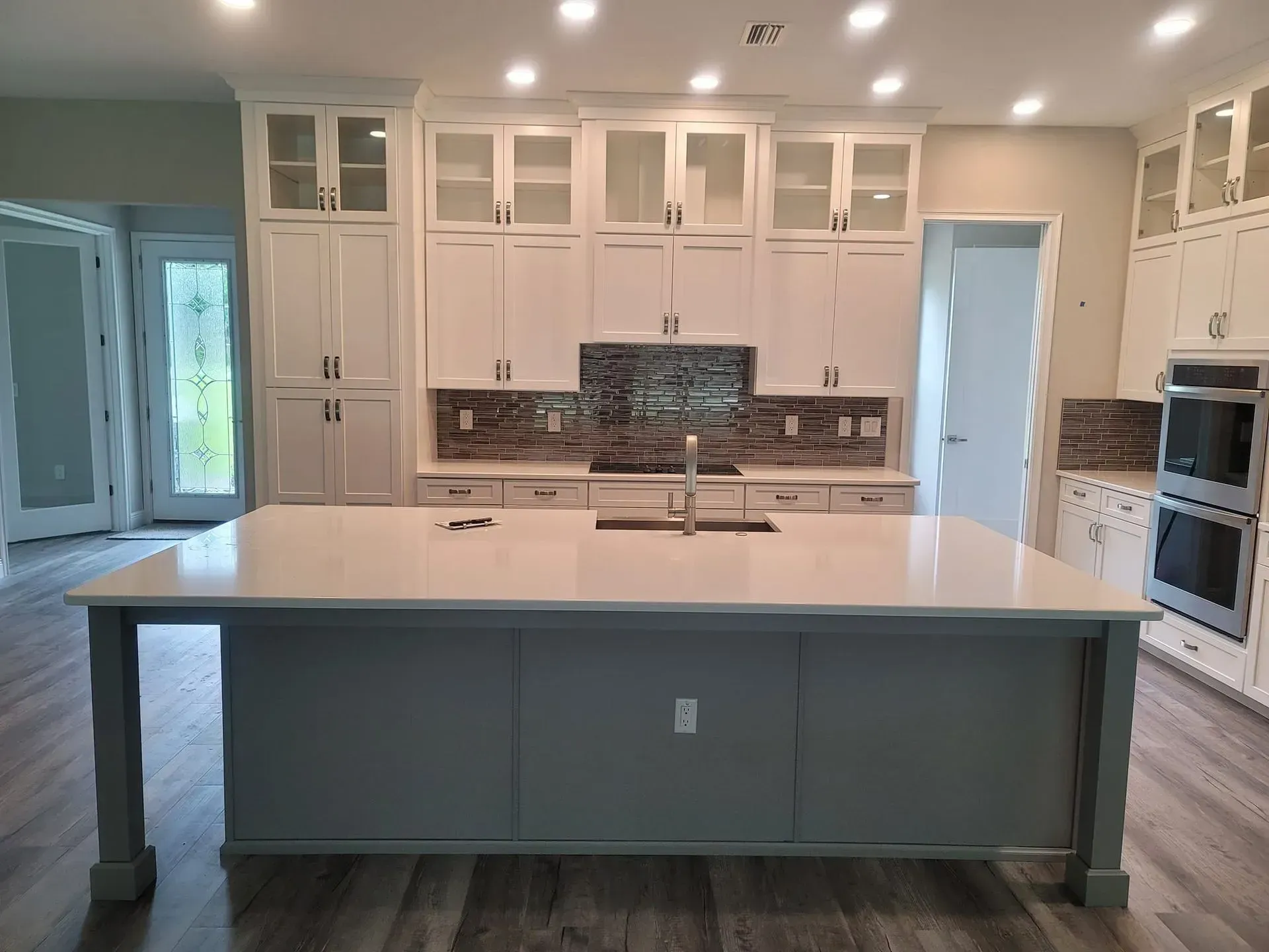 White kitchen with island, cabinets, backsplash, and stainless steel appliances.