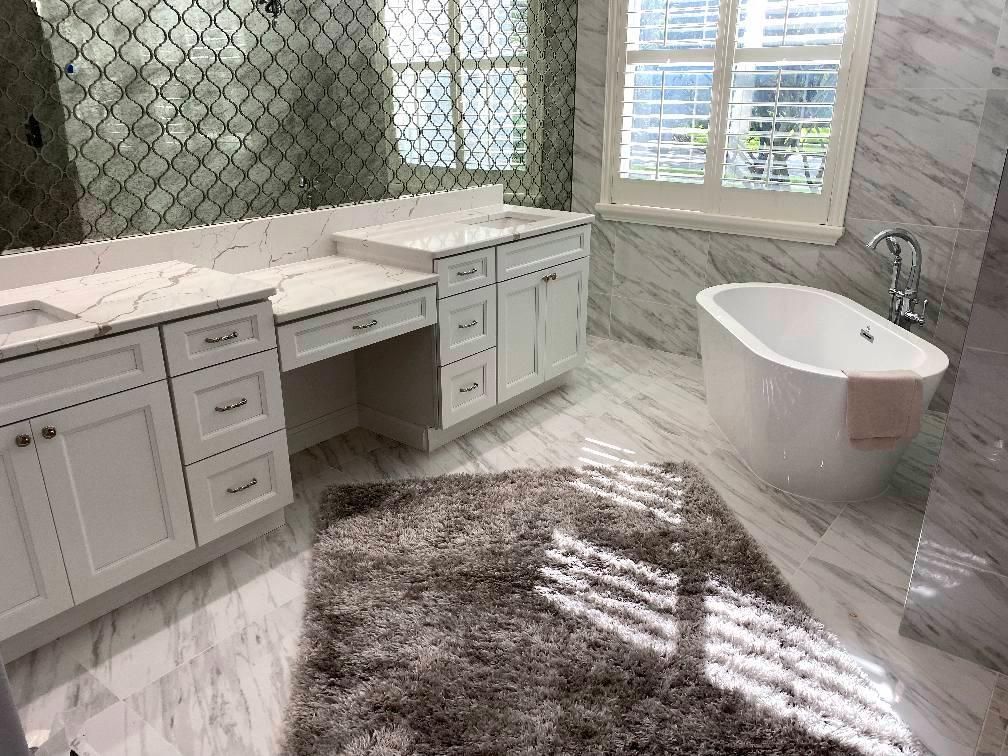 A bathroom with two sinks, a tub, and a rug