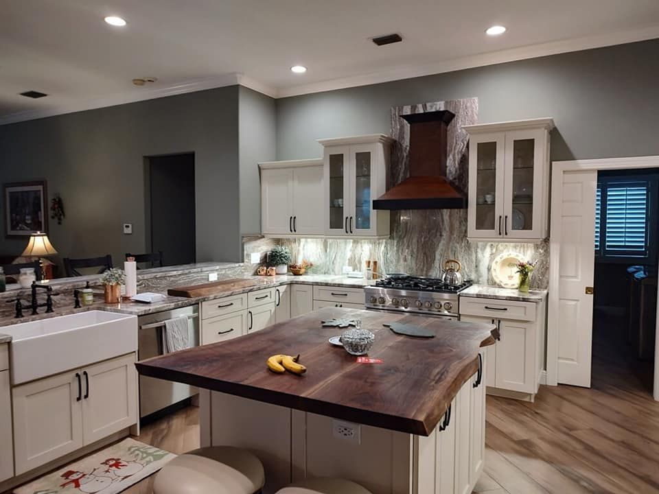 A kitchen with white cabinets and a wooden counter top
