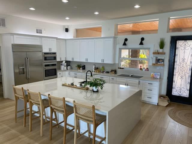 A kitchen with white cabinets and stainless steel appliances and a large island
