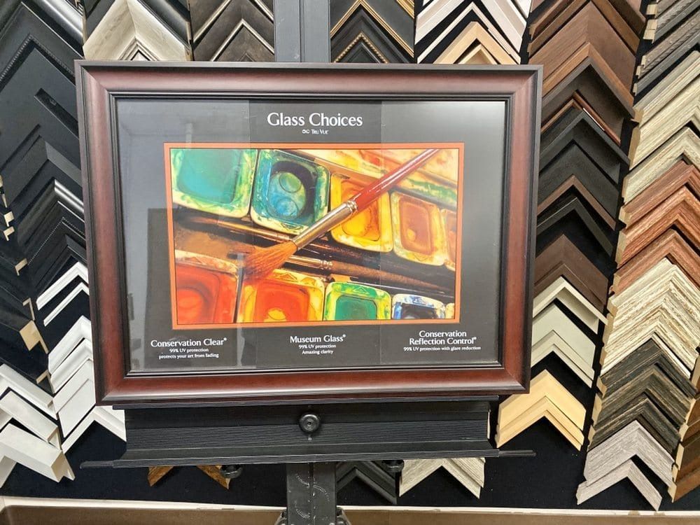 Framed artwork with colorful paint palette; displayed in a frame store with various molding samples.